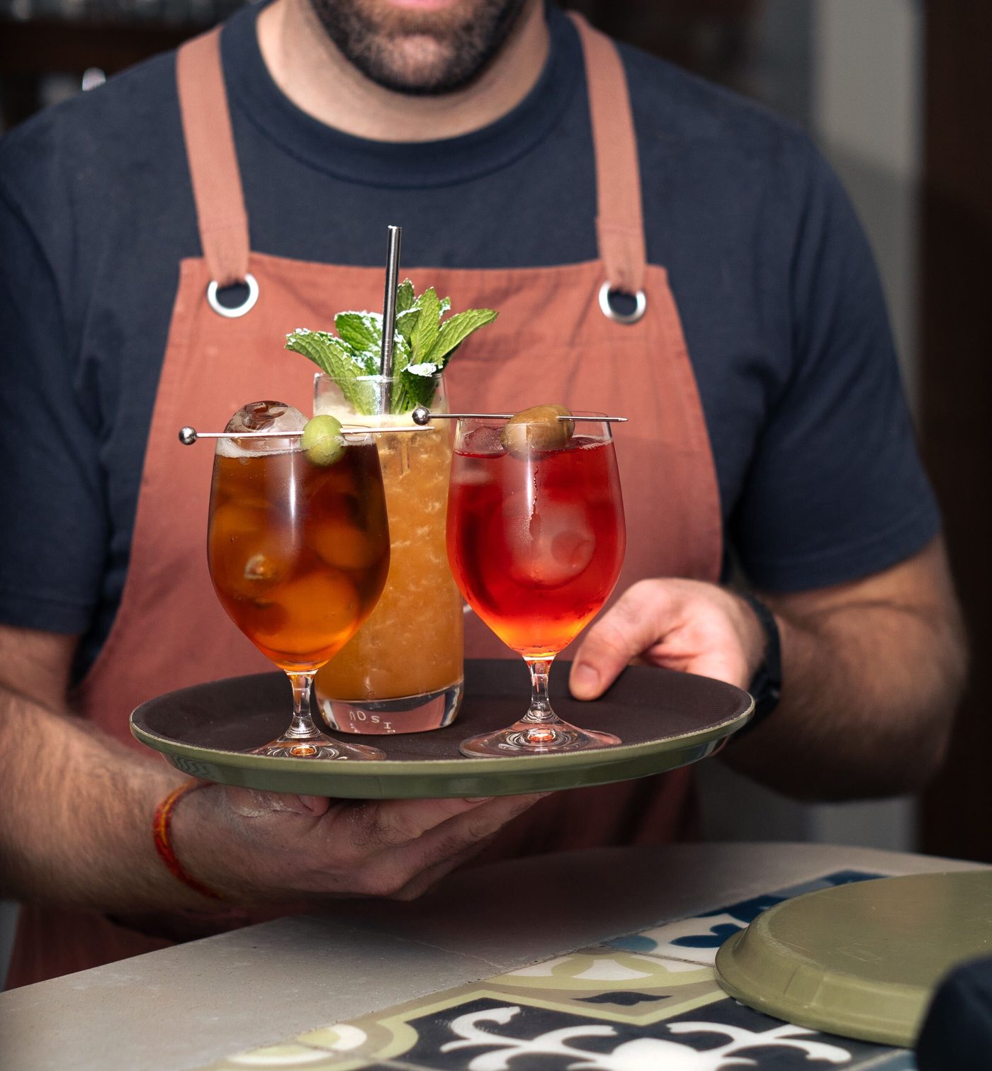 A bartender at Bisou Bisou presenting a tray of finished cocktails