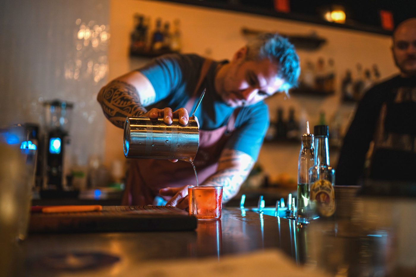 Greg Buda pouring a cocktail from a mixing tin